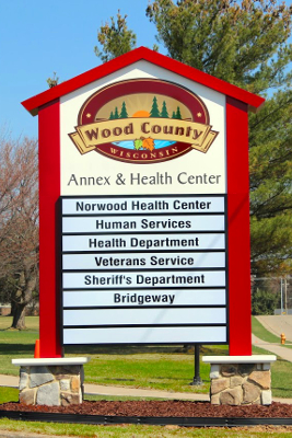 Wood County Annex and Health Center outdoor sign, listing Norwood Health Center, Human Services, Health Department, Veterans Service, Sheriff's Department, and Bridgeway.